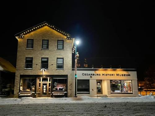 Cedarburg History Museum at night, featuring festive lights and snow-covered ground.