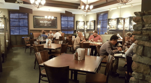 A cozy restaurant interior with wooden tables, chairs, and patrons enjoying meals in a warm, inviting atmosphere.