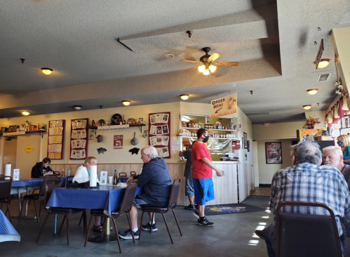 A cozy diner interior with patrons at tables, a counter with a menu, and a server in a mask walking by.