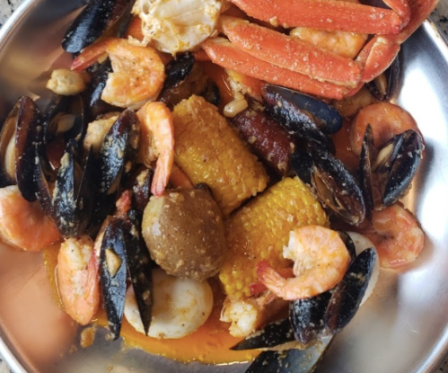 A seafood platter featuring shrimp, crab, mussels, corn, and sausage in a flavorful sauce.