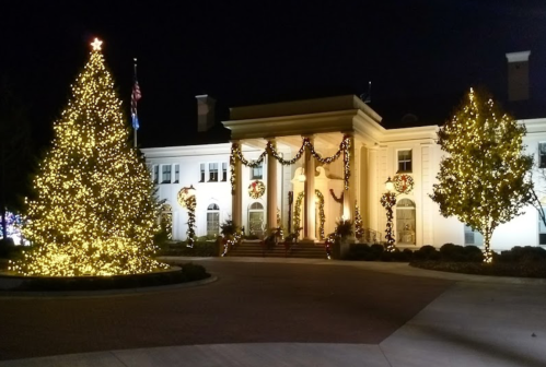 A beautifully lit building adorned with holiday decorations and a large Christmas tree at night.