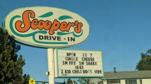 Sign for Scooper's Drive-In displaying menu items: single cheese, small fry, small shake, kid chili dogs, and prices.