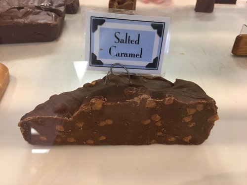 A piece of salted caramel fudge displayed in a shop, with a sign indicating its flavor.
