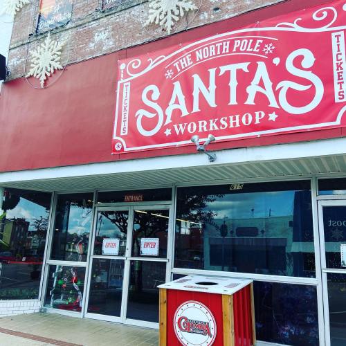 A festive storefront with a sign reading "Santa's Workshop" and decorative snowflakes above the entrance.