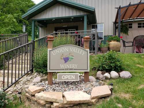 Sign for Union Valley Winery, established in 2010, with "OPEN" displayed in front of a building and landscaped area.