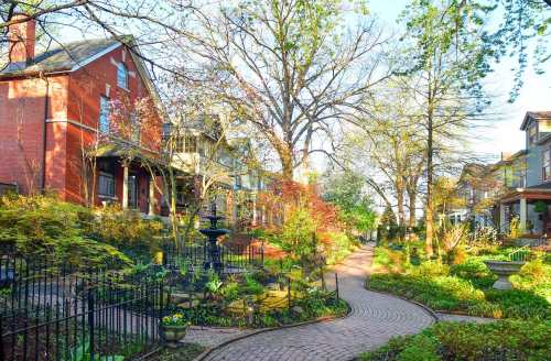 A charming neighborhood with brick houses, lush gardens, and a winding path surrounded by trees and greenery.