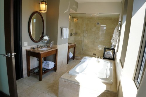 A modern bathroom featuring a bathtub, shower, sink, and elegant decor with natural light.