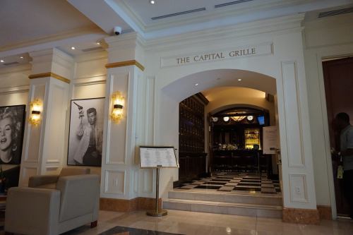 Interior of The Capital Grille restaurant, featuring elegant decor and a view of the dining area through an archway.