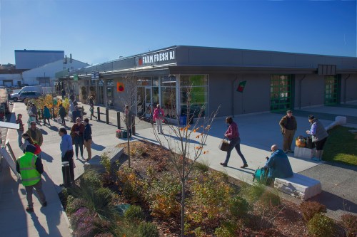 A bustling outdoor market scene with people shopping and walking near a store called "Farm Fresh."