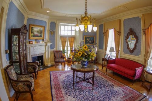A cozy living room with elegant furniture, a floral centerpiece, and warm lighting, featuring a fireplace and decorative walls.