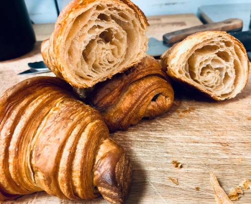 Freshly baked croissants, cut open to reveal flaky, spiral layers, resting on a wooden surface.