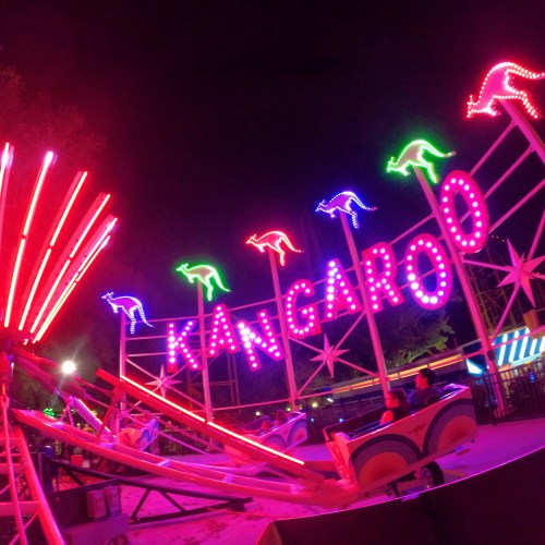 Bright neon sign reading "KANGAROO" with colorful lights and kangaroo silhouettes at a nighttime amusement park.
