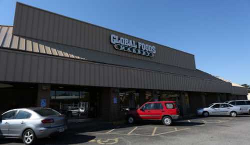 Exterior of Global Foods Market, featuring a large sign and parked cars in a sunny parking lot.