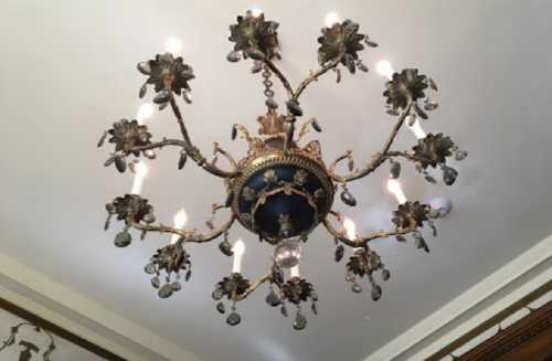 A decorative chandelier with floral designs and multiple light bulbs, adorned with hanging crystals.