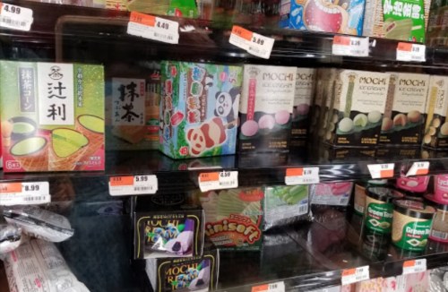 A display of various mochi and snacks, including matcha and panda-themed packaging, in a store shelf.