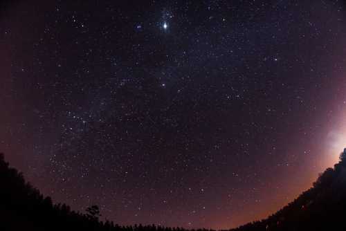 A starry night sky filled with countless stars, with a gradient from dark blue to purple near the horizon.