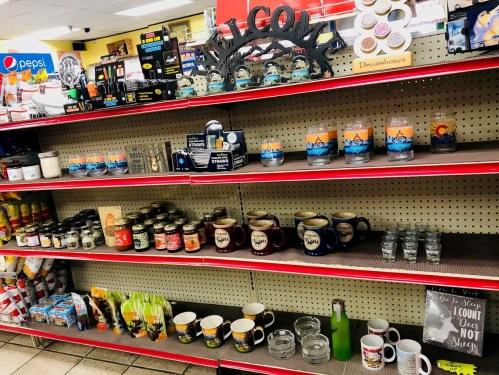 A store shelf displaying various candles, mugs, and decorative items in a colorful arrangement.
