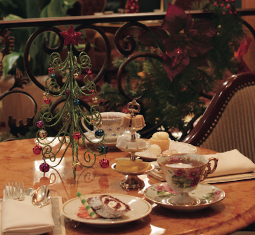 A festive table setting with a small Christmas tree, elegant tea cup, and holiday decorations in a cozy setting.