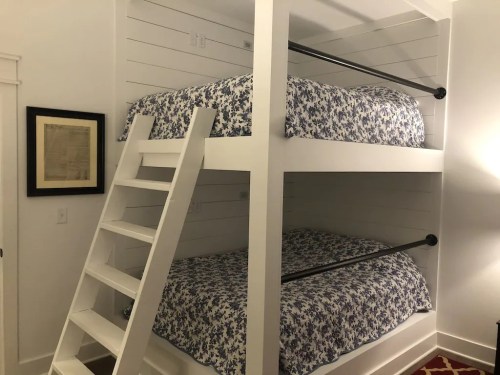 A cozy room featuring a white bunk bed with floral-patterned bedding and a wooden ladder.