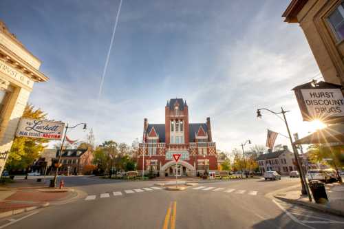 Historic brick building at a town intersection, with clear skies and autumn trees in the background.