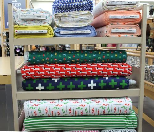A display of colorful fabric rolls stacked on a shelf, featuring various patterns and designs.
