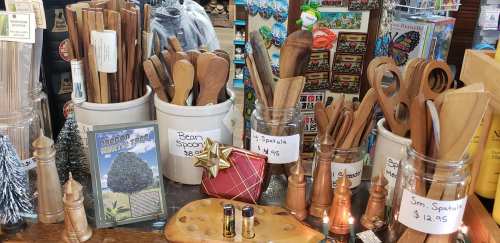 A display of wooden kitchen utensils, including spoons and spatulas, with price tags and decorative items in a store.