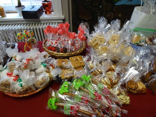 A festive display of assorted wrapped treats, including cookies, candies, and rice crispy treats on a red tablecloth.