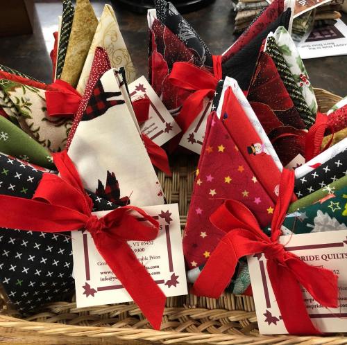A basket filled with colorful fabric triangles tied with red ribbons, each labeled with a tag.