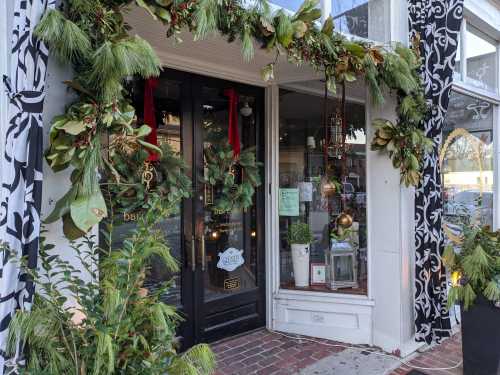 A festive storefront adorned with greenery, red ribbons, and holiday decorations, inviting customers inside.