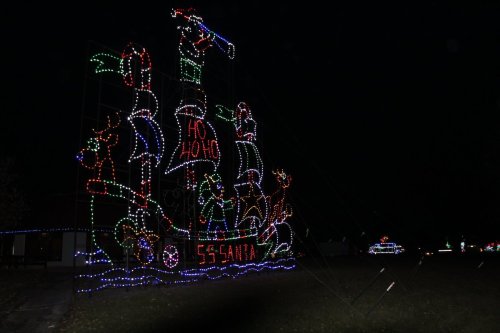 A colorful holiday light display featuring Santa on a ship with reindeer and festive decorations against a dark background.