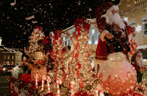 A festive holiday scene with decorated trees, Santa figures, and snowflakes, illuminated by colorful lights.