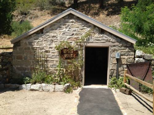A rustic stone building with a wooden sign reading "Visitors Center" and a pathway leading to the entrance.