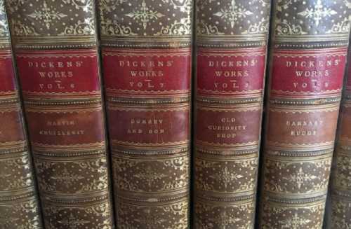 A close-up of vintage leather-bound books by Charles Dickens, featuring titles and decorative spines.