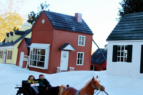 A miniature village scene with colorful houses and a horse-drawn carriage featuring two figures.