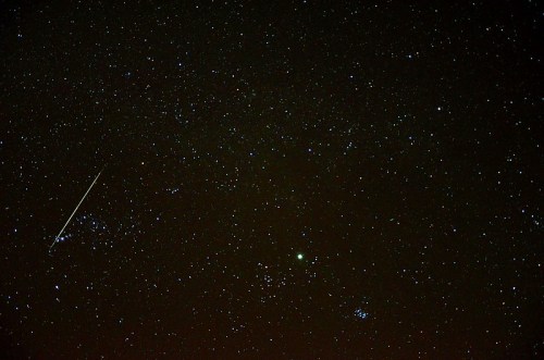 A starry night sky filled with countless stars, featuring a bright comet streaking across the scene.