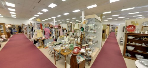 A spacious antique store aisle filled with vintage items, clothing, and decorative pieces on display.