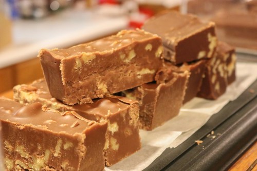 A close-up of stacked chocolate fudge bars with nuts, resting on a tray lined with parchment paper.