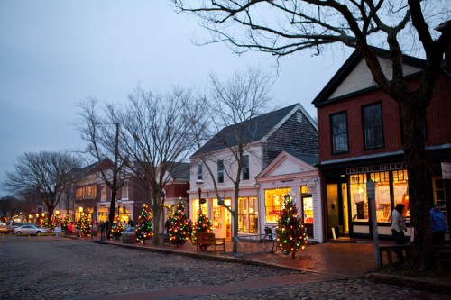 A charming street lined with festive shops and decorated Christmas trees, illuminated in the evening glow.