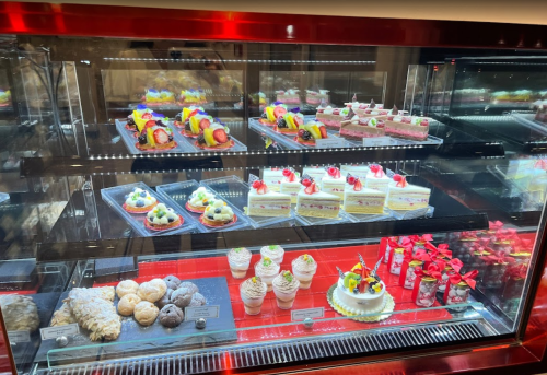 A display case filled with colorful desserts, including cakes, pastries, and fruit-topped treats.