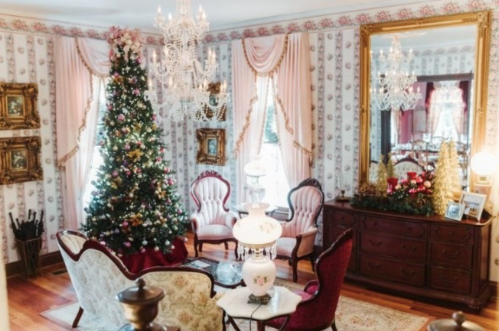 A cozy, elegantly decorated living room with a Christmas tree, vintage furniture, and ornate chandeliers.