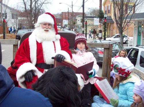 Santa Claus sits in a sleigh with children, surrounded by festive decorations and a wintery town scene.