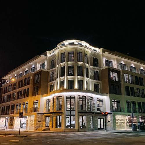 A modern building illuminated at night, featuring large windows and a stylish architectural design.