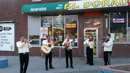 A mariachi band performs outside El Dorado Seafood restaurant, with colorful signage and a lively atmosphere.