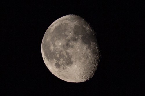 A close-up view of the moon, showcasing its craters and surface details against a dark sky.