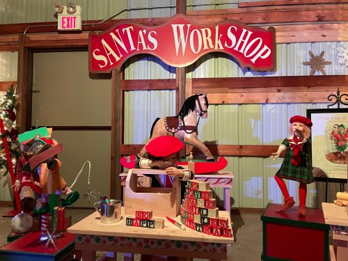 A festive display of Santa's Workshop featuring toys, a rocking horse, and cheerful decorations.