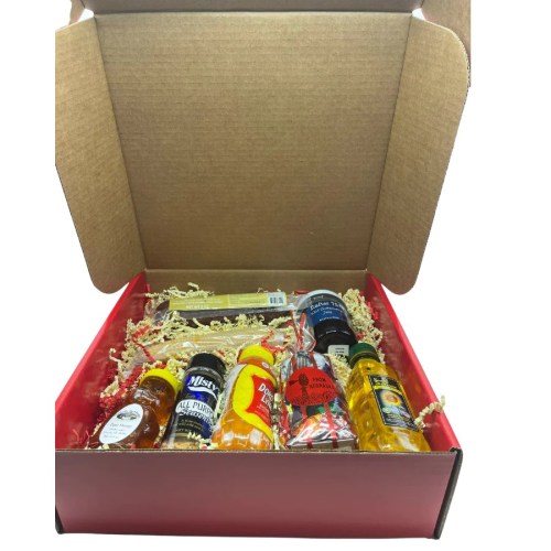 A gift box filled with various small bottles and treats, arranged on red and shredded paper.