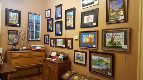 A cozy room featuring a wooden dresser and a variety of framed artwork on the walls.