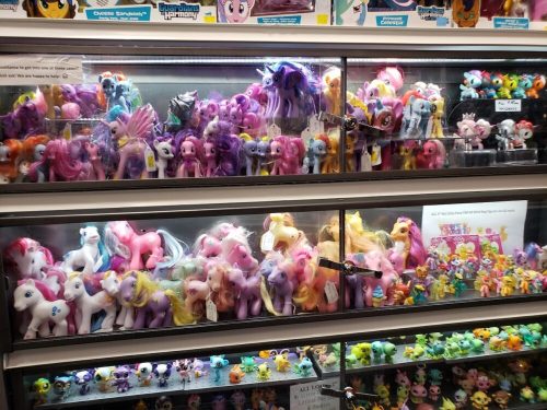 A display case filled with colorful My Little Pony toys and figures in various styles and sizes.