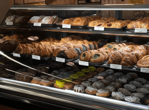 A display case filled with a variety of pastries, including croissants, donuts, and sweet rolls, all beautifully arranged.