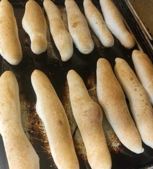 Freshly baked breadsticks arranged on a baking tray, golden brown with a slightly crispy texture.